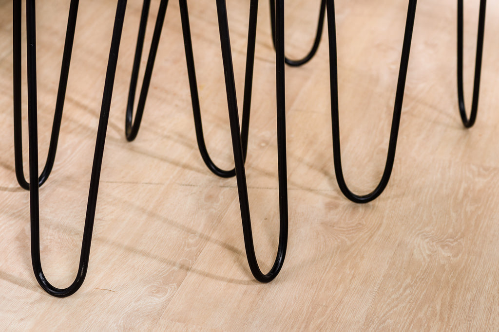 Zwarte metalen tafelpoten op licht houten vloer, geschakeerd en modern design met speelse vormen.