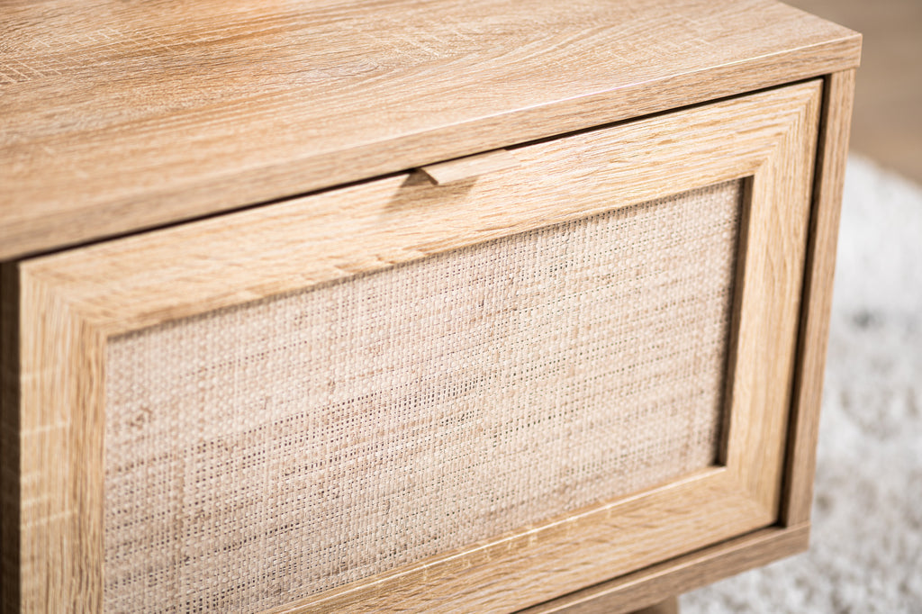 Houten kastje met geweven rieten deurpaneel op een zachtgekleurd tapijt.