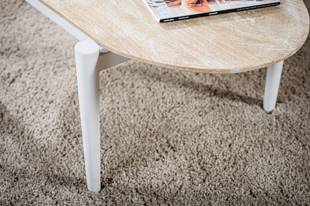 Houten salontafel met witte poten op beige tapijt, tijdschrift "Marie Claire" van augustus 2018 bovenop.