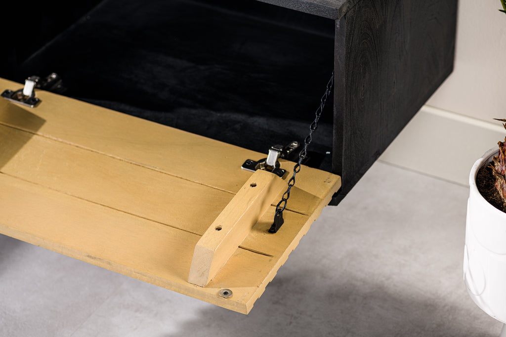 Houten klep met metalen scharnieren en kettingen, openend van zwart kastje op grijze vloer.