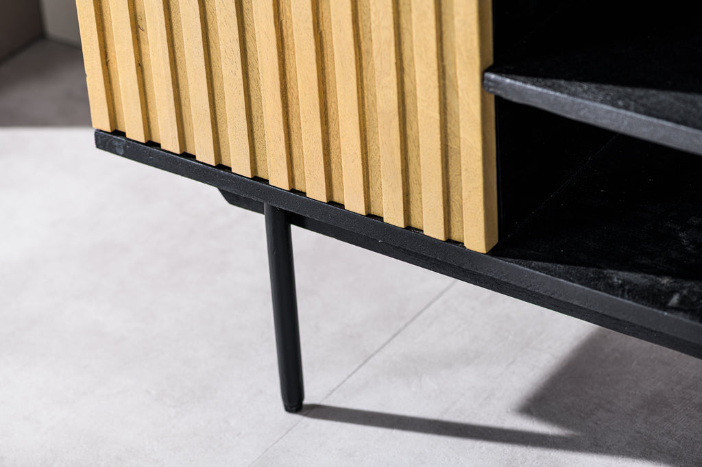 Strakke houten kast met verticale ribbels en zwarte poten op een lichte vloer.