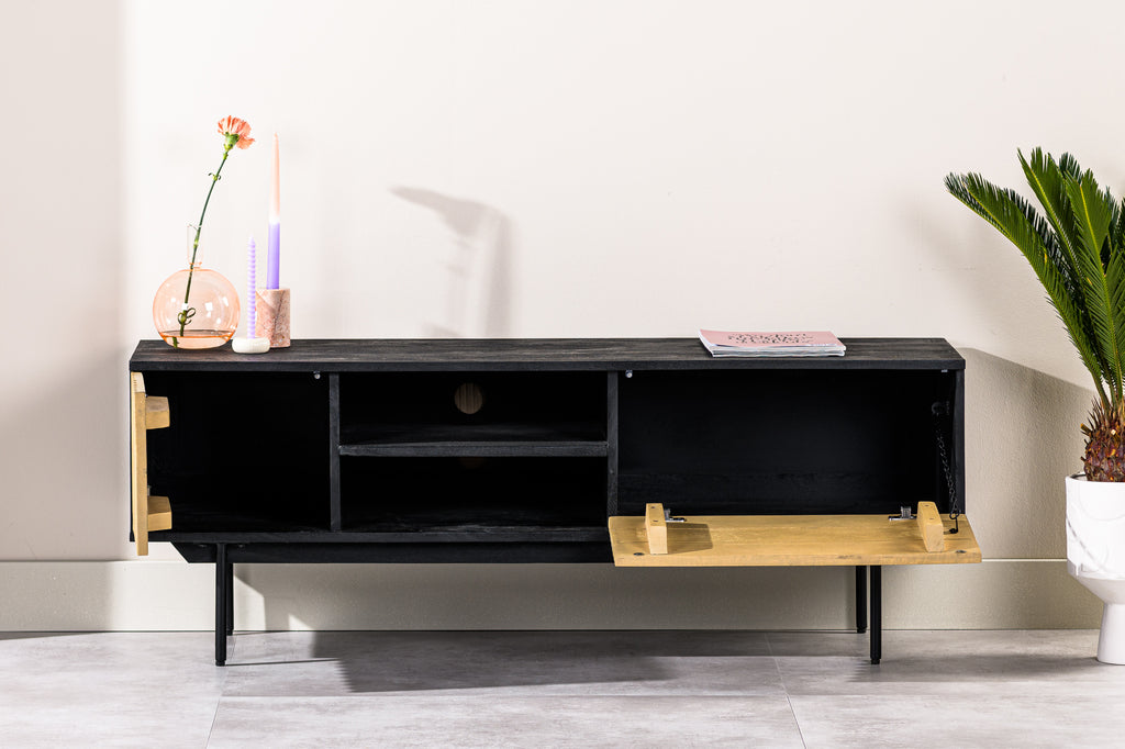 Zwart tv-meubel met open kast, goudkleurige deurtjes, vaas met bloem, kaarsen en tijdschrift erbovenop.