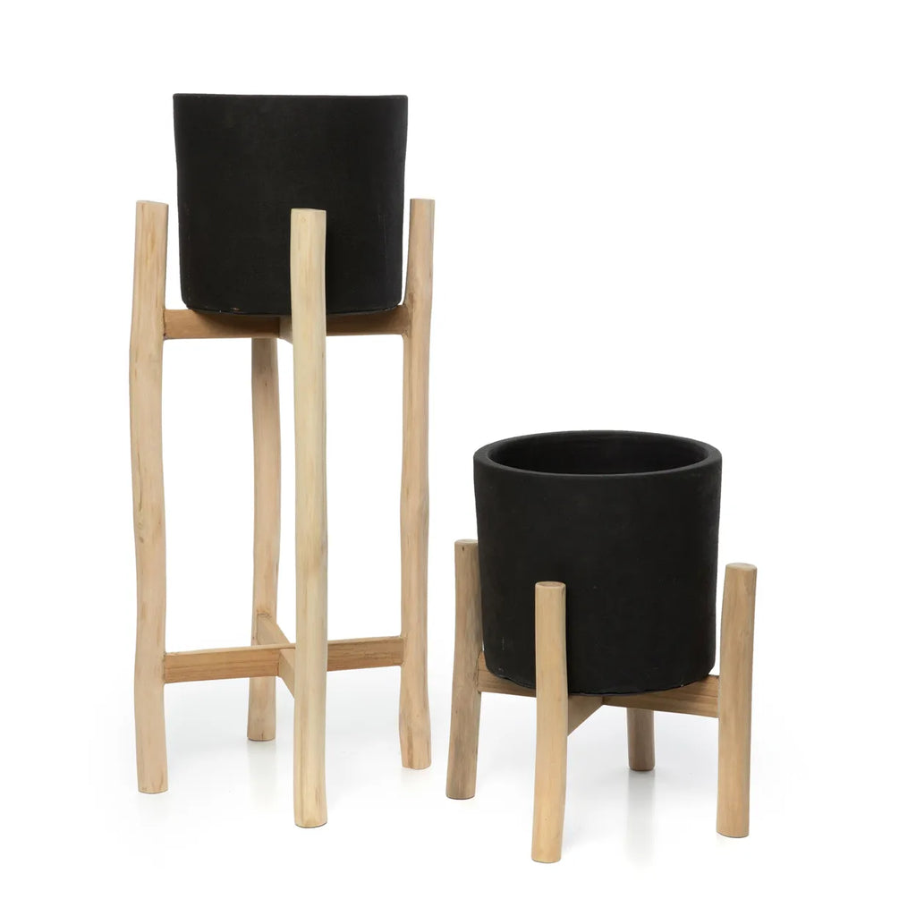 Twee zwarte plantenpotten op houten standaarden, één hoog en de ander laag, met een minimalistisch design.