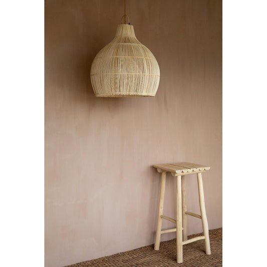 Rotan hanglamp en houten kruk voor een aardetint muur, op een rustieke, geweven vloer.