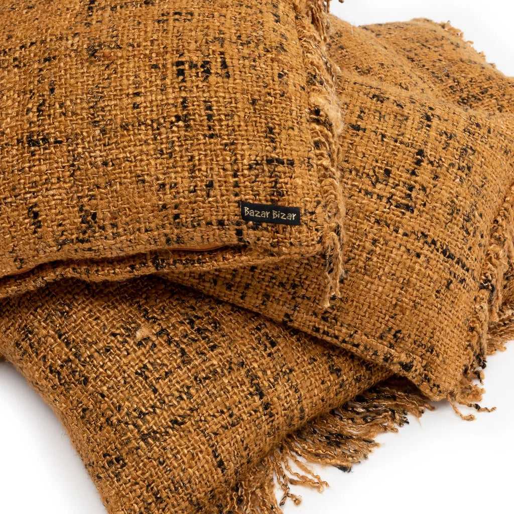 Drie rustieke bruine kussens van jute met zwarte accenten, label "Bazar Bizar" zichtbaar.