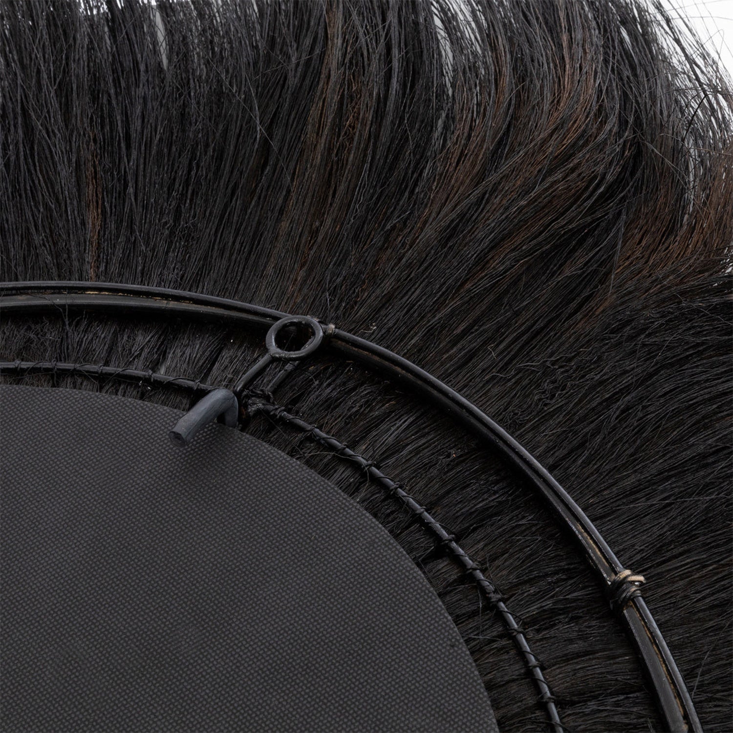 Close-up van zwarte borstelharen rond een ronde rand met metalen ring, gedetailleerd en textuurrijk.