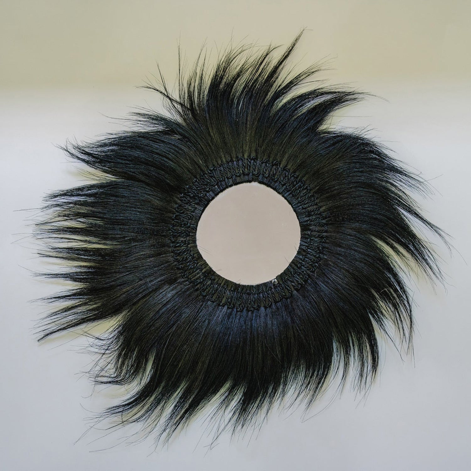 Rond decoratief spiegelontwerp met zwarte synthetische haren, straalt een levendige en unieke esthetiek uit.