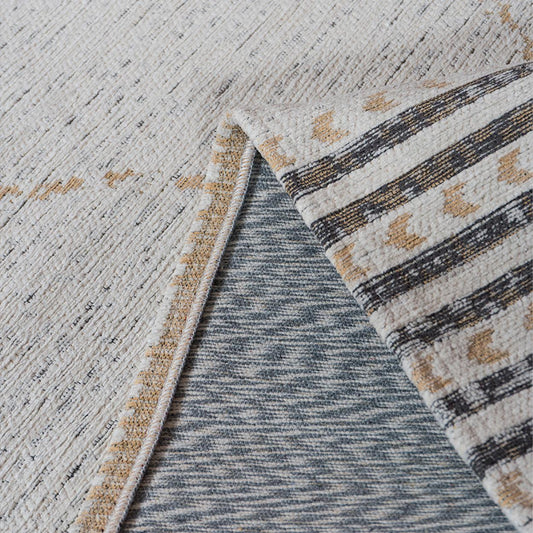 Close-up van een tapijt met beige en grijze patronen, opengeslagen hoek toont contrasterende strepen.