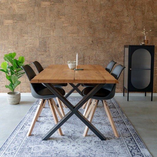 Moderne eetkamer met houten tafel, zwarte stoelen, vintage vloerkleed, groene plant en zwarte kast.