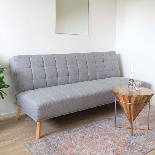 Stijlvolle woonkamer met grijze gestoffeerde bank, houten bijzettafel met kaarsen en kleurrijk oosters tapijt.