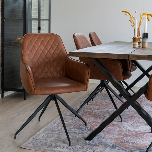 Bruine leren eetkamerstoelen met ruitpatroon, houten tafel met metalen poten, vaas met bloemen, vloerkleed.