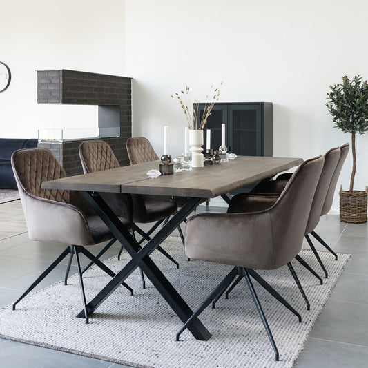 Moderne eetkamer met donkerhouten tafel, zes bruine fluwelen stoelen, witte kaarsen en neutrale decoratie.