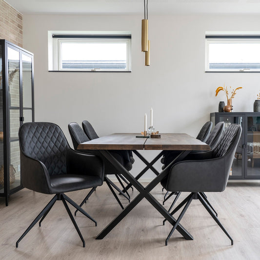 Moderne eetkamer met zwart lederen stoelen, houten tafel, minimalistische decoratie en gouden hanglamp.