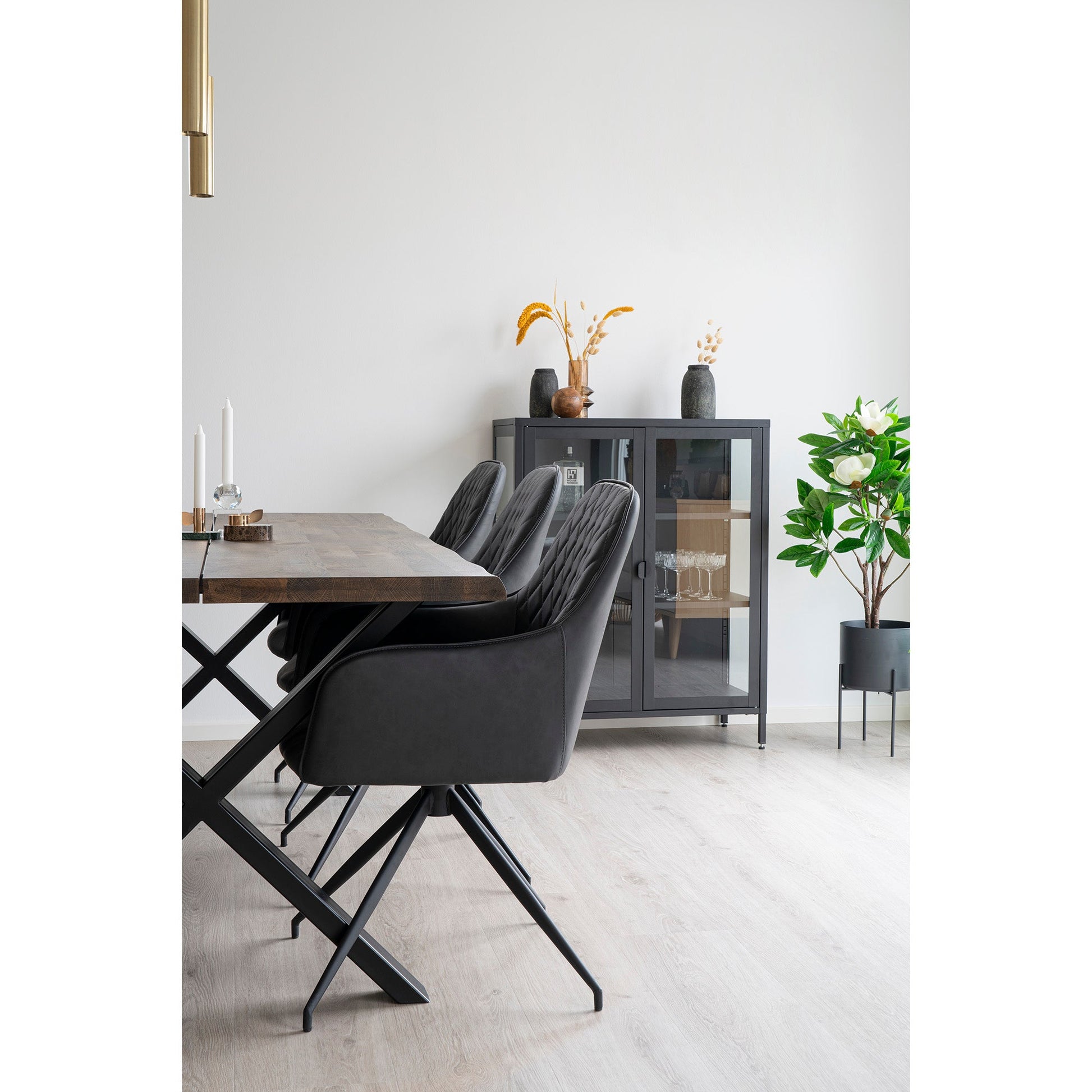 Stijlvolle eetkamer met houten tafel, zwarte stoelen, glazen kast, en decoratieve planten voor elegante sfeer.