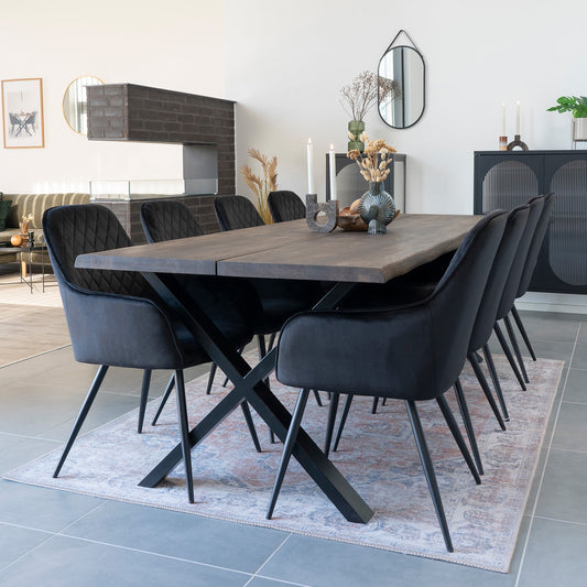 Stijlvolle eethoek met donkere houten tafel en acht zwarte stoelen, op een sierlijk tapijt.