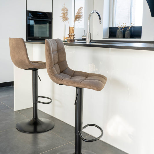 Twee bruine barkrukken voor een moderne witte keukenbar met grijs aanrecht en zilverkleurige kraan.