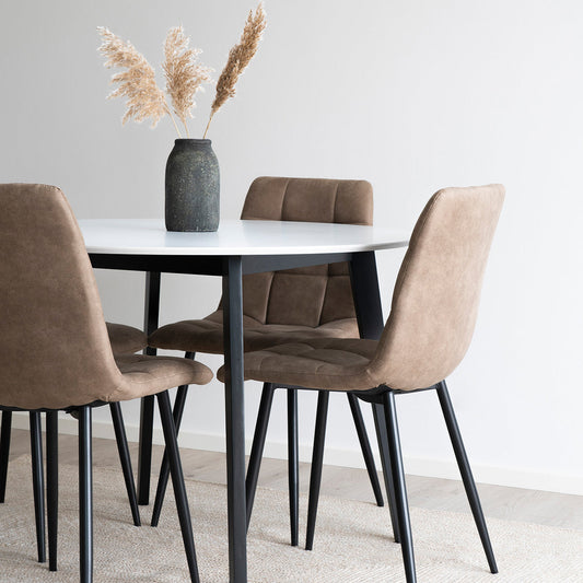 Bruin gestoffeerde stoelen rond een witte tafel met zwarte poten, vaas met droogbloemen in het midden.