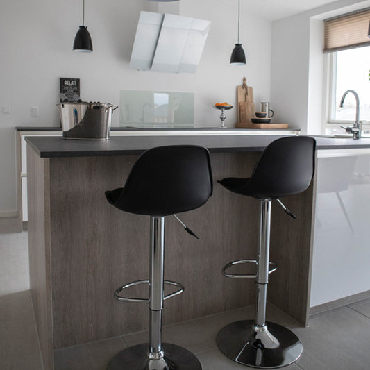 Moderne keuken met twee zwarte barkrukken, glazen fruitschaal, rvs-emmer en strak wit design.