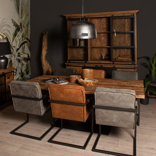 Stijlvolle eetkamer met houten tafel, bruine en grijze stoelen, metalen lamp en planten op houten vloer.