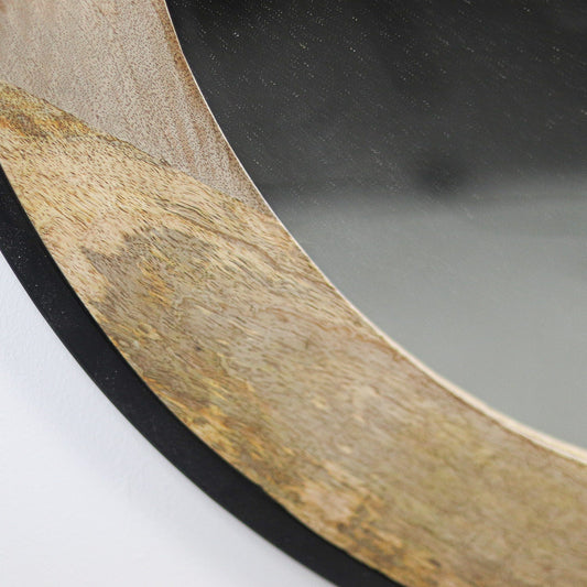 Ronde spiegel met een houten rand, glad afgewerkt en subtiel rustiek, weerspiegelt een donkergrijze achtergrond.