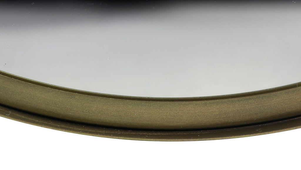 Rond bronzen spiegel met glad, glanzend oppervlak en subtiele reflecties boven een lichte achtergrond.