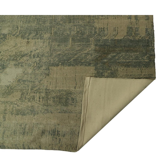 Grote groene en beige tapijt met abstract patroon, hoek opgerold om de effen onderkant te tonen.