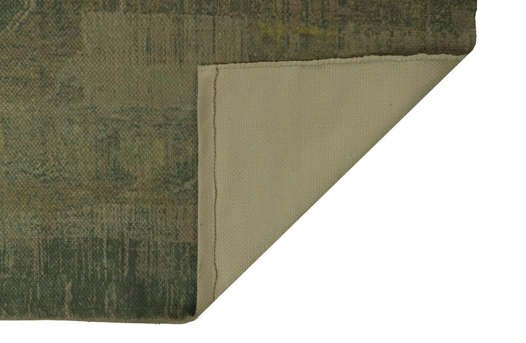 Groene stoffige vloerkleed, gevouwen hoek onthult beige achterkant, rustieke uitstraling.