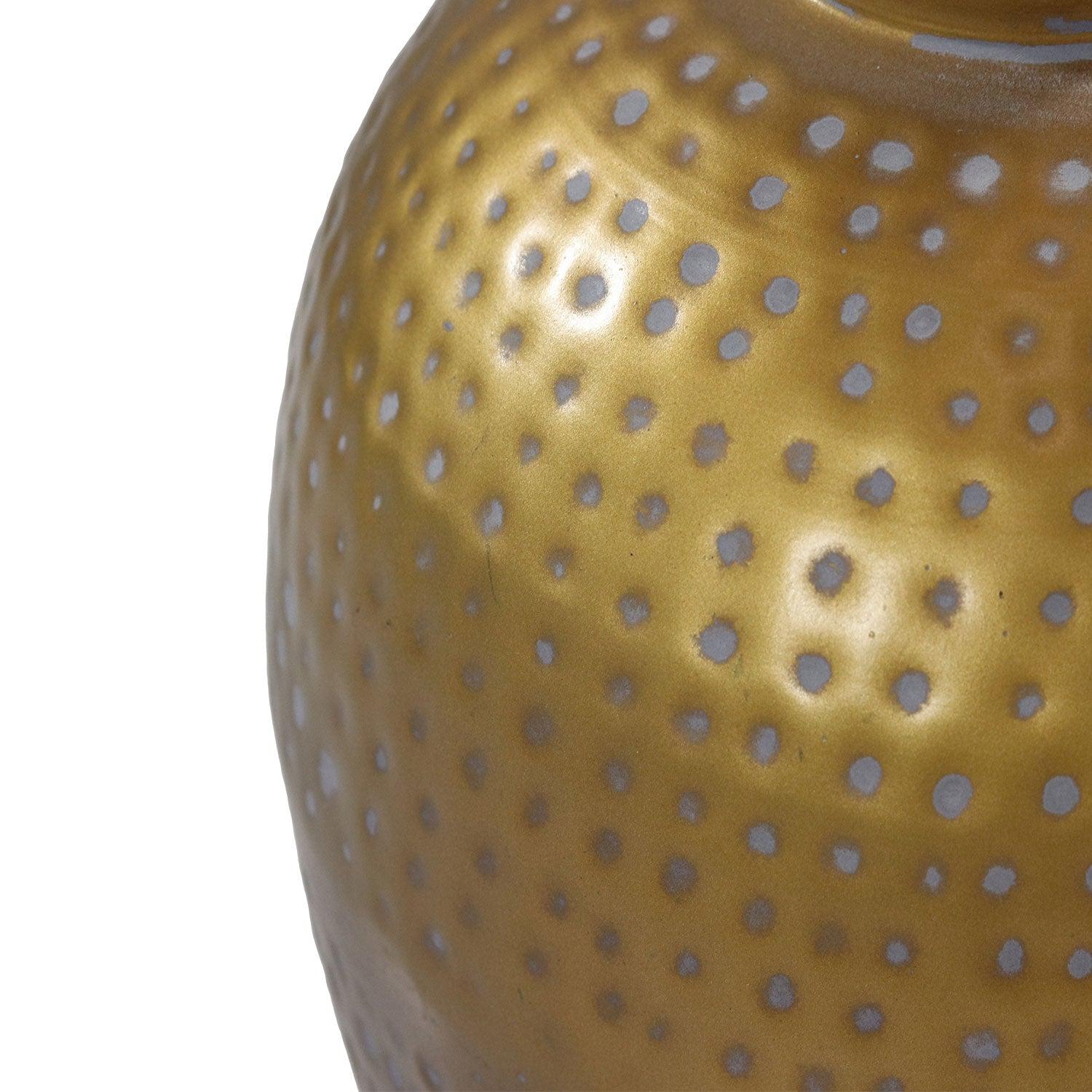 Goudkleurige vaas met glanzende afwerking en een patroon van witte stippen, met een artistiek oppervlak.