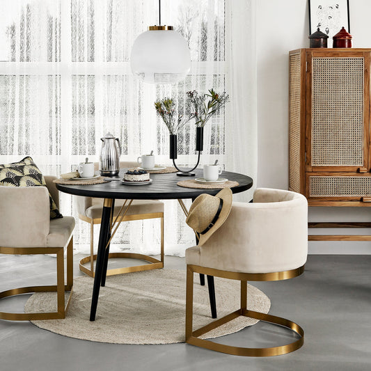 Stijlvolle eetkamer met ronde zwarte tafel, beige stoelen met gouden accenten en modern tafelservies.