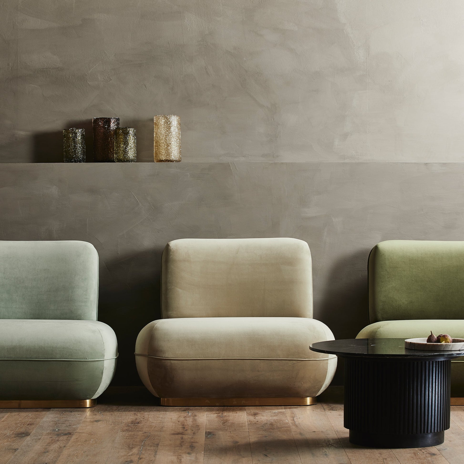 Stijlvolle fauteuils in pastelkleuren op houten vloer, met donkere salontafel en stijlvolle vaasdecoratie erboven.