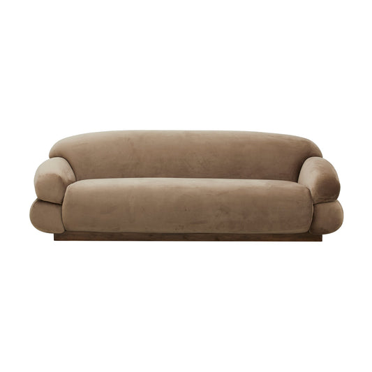 Zachte beige fluwelen driezitsbank met afgeronde armleuningen en massief houten onderstel tegen witte achtergrond.