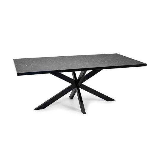 Minimalistische tafel met zwart marmeren blad en opvallend gekruist metalen onderstel.