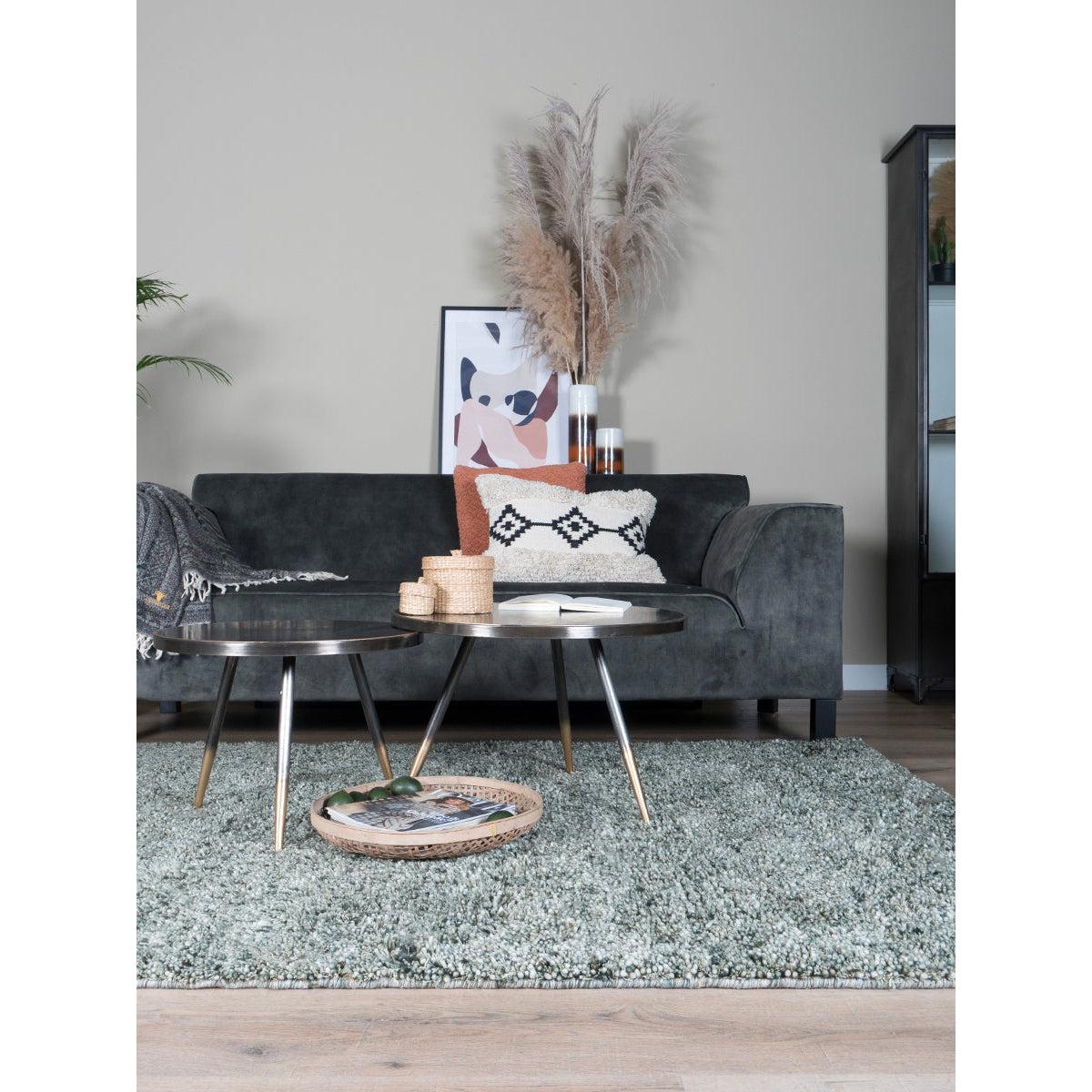 Stijlvolle woonkamer met zwarte bank, sierkussens, moderne bijzettafels en gedroogde pampasgrasdecoratie.