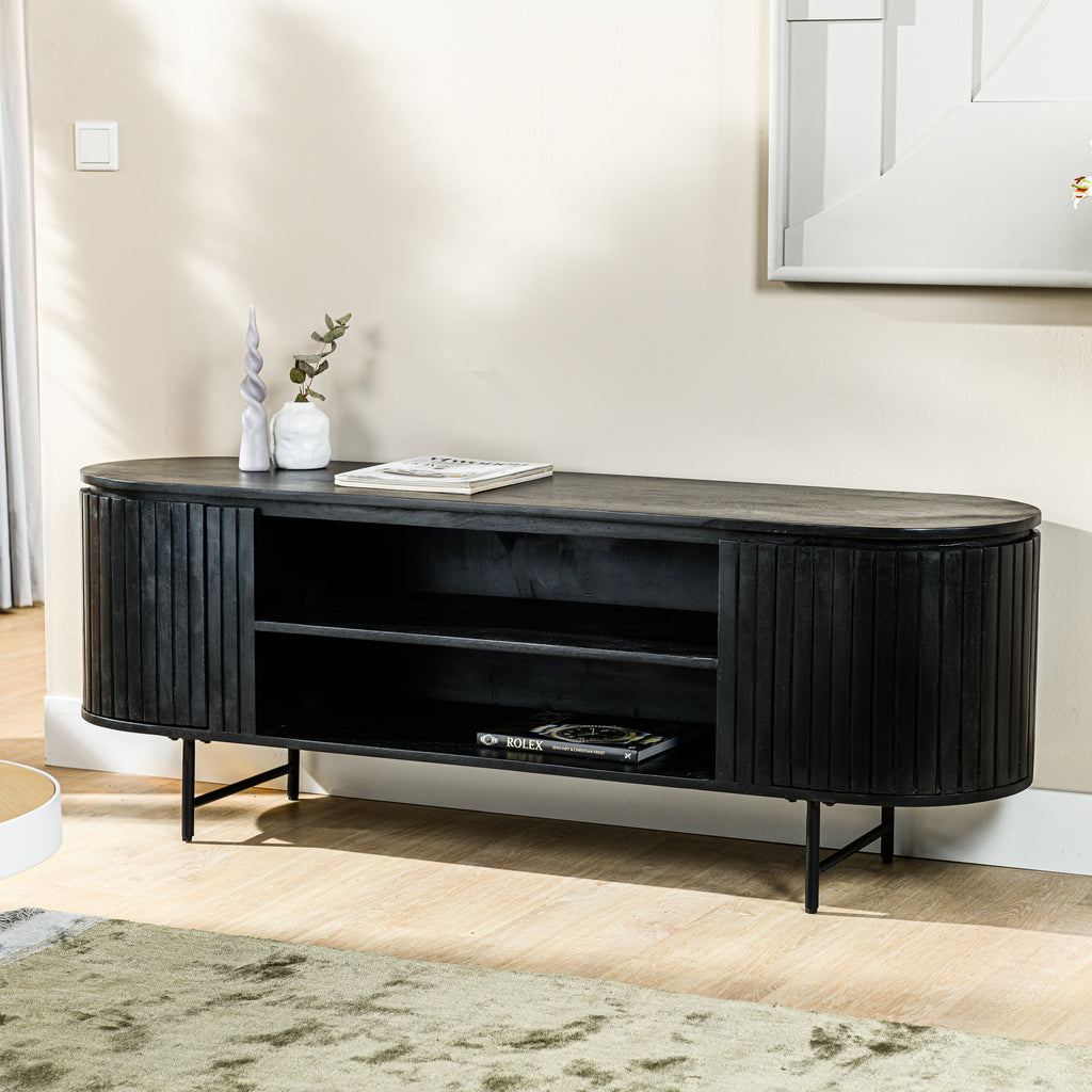 Zwart houten dressoir met open planken, gedecoreerd met tijdschriften, een vaas en een kaars.