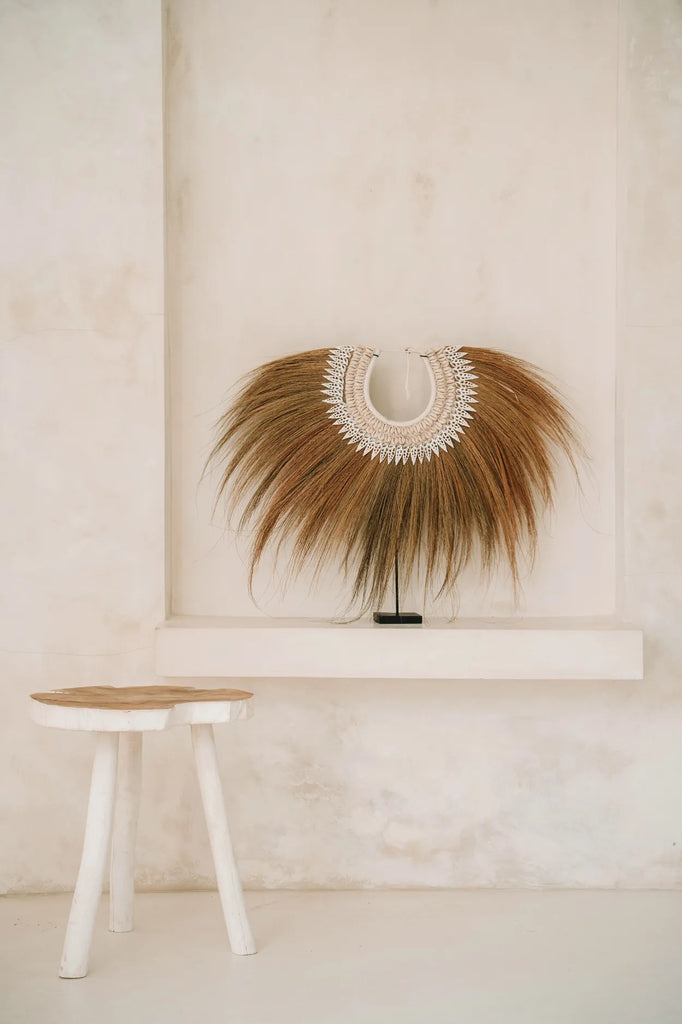 Bruin verenjuweel en witte houten kruk tegen een minimalistische beige achtergrond.