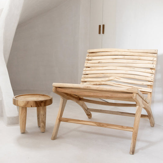 Houten loungestoel en rond bijzettafeltje in een minimalistisch witte kamer met zachte lichtinval.