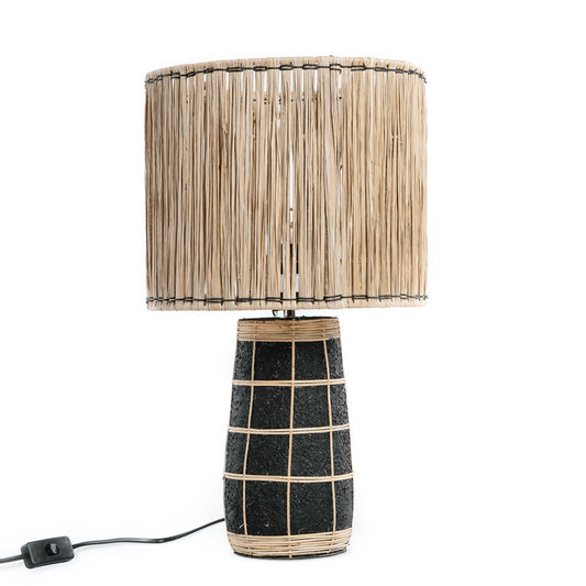 Zwarte lamp met rotan raster en cilindrische kap van stroharen, met een snoer en schakelaar.