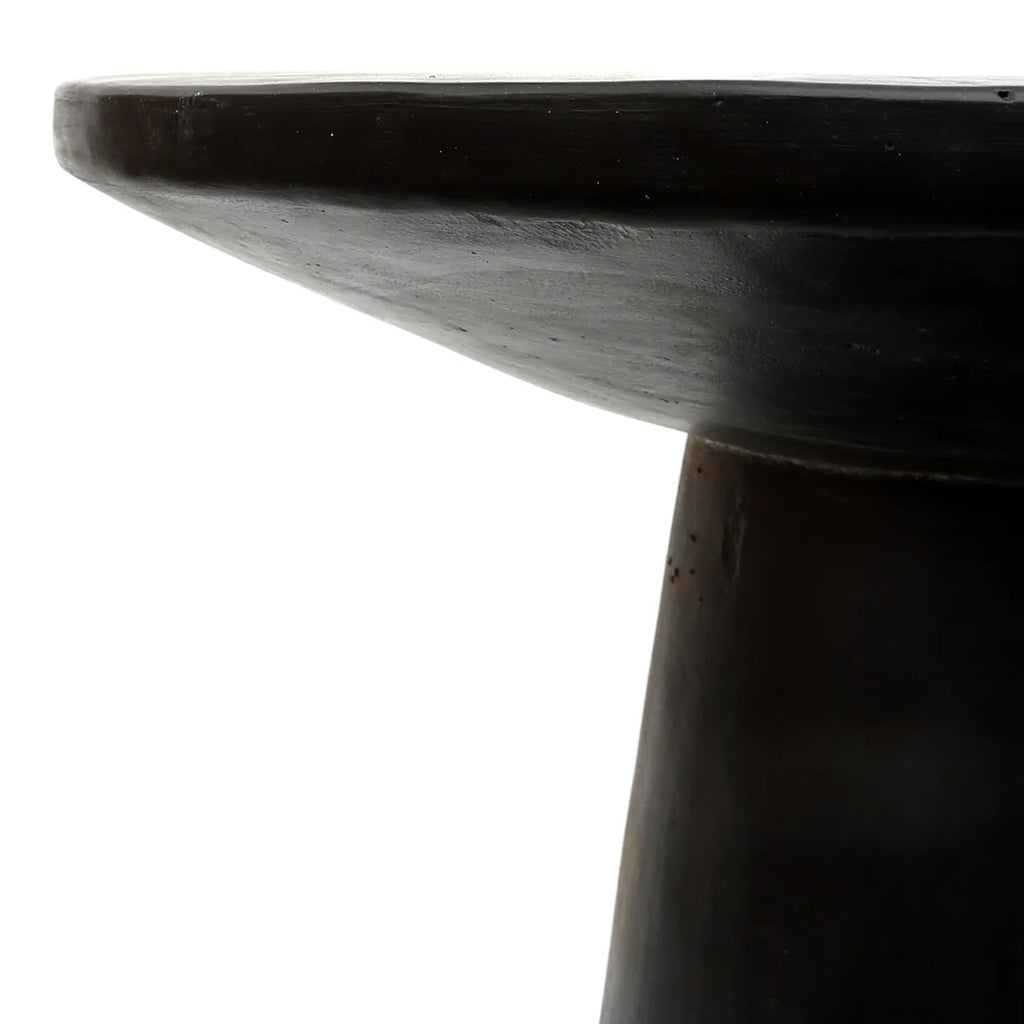 Close-up van een robuuste, zwarte houten tafel met een glad afgewerkte ronde tafelrand.