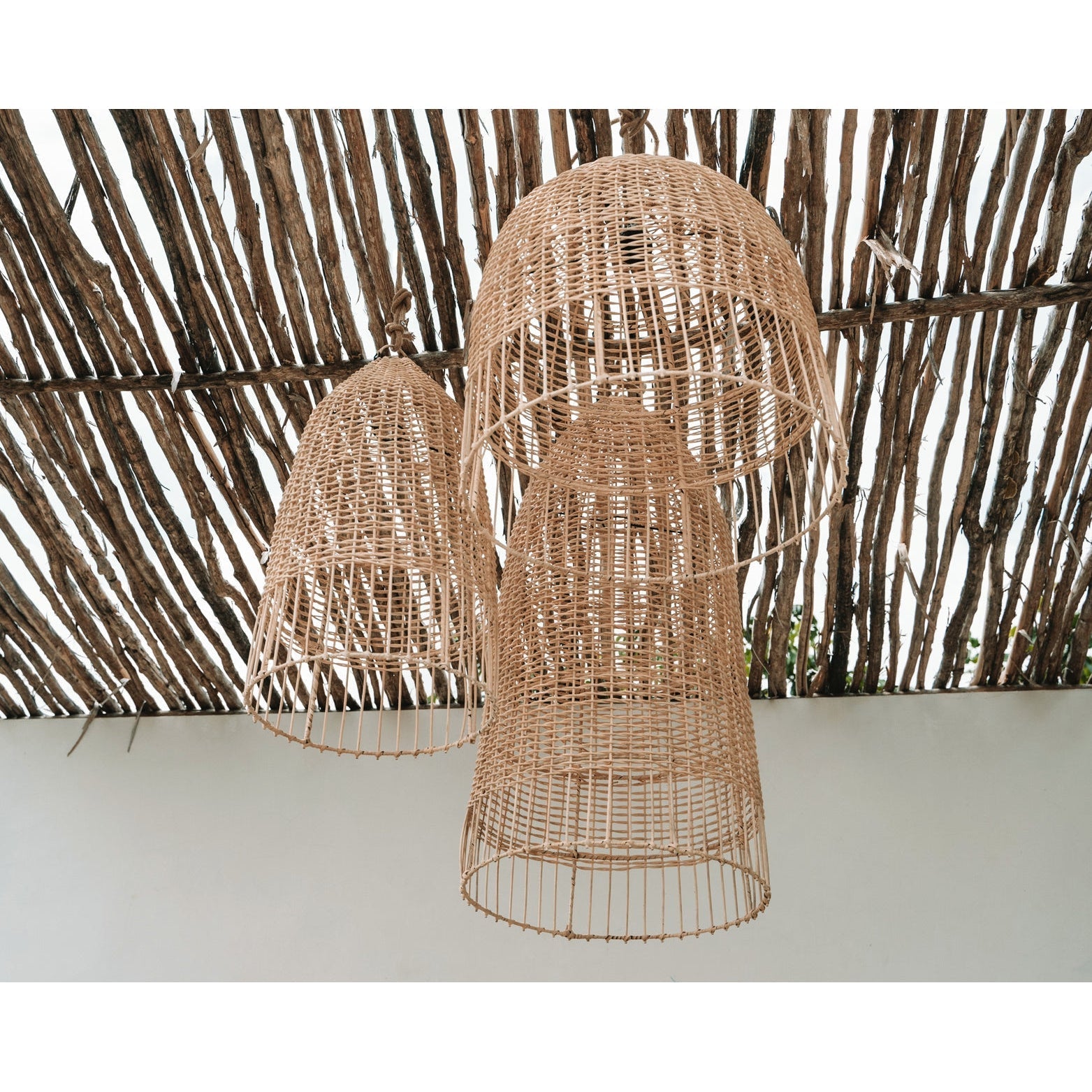 Grote rotan hanglampen onder een rustiek houten plafond, speling van licht en schaduw in een natuurlijke setting.