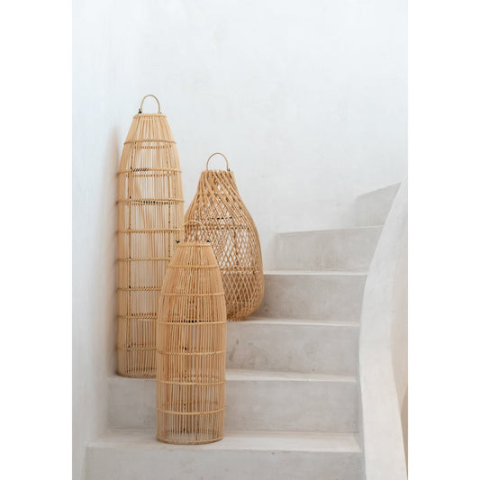Drie rotan lantaarns in natuurlijke tinten staan artistiek opgesteld op een witte, gebogen trap.