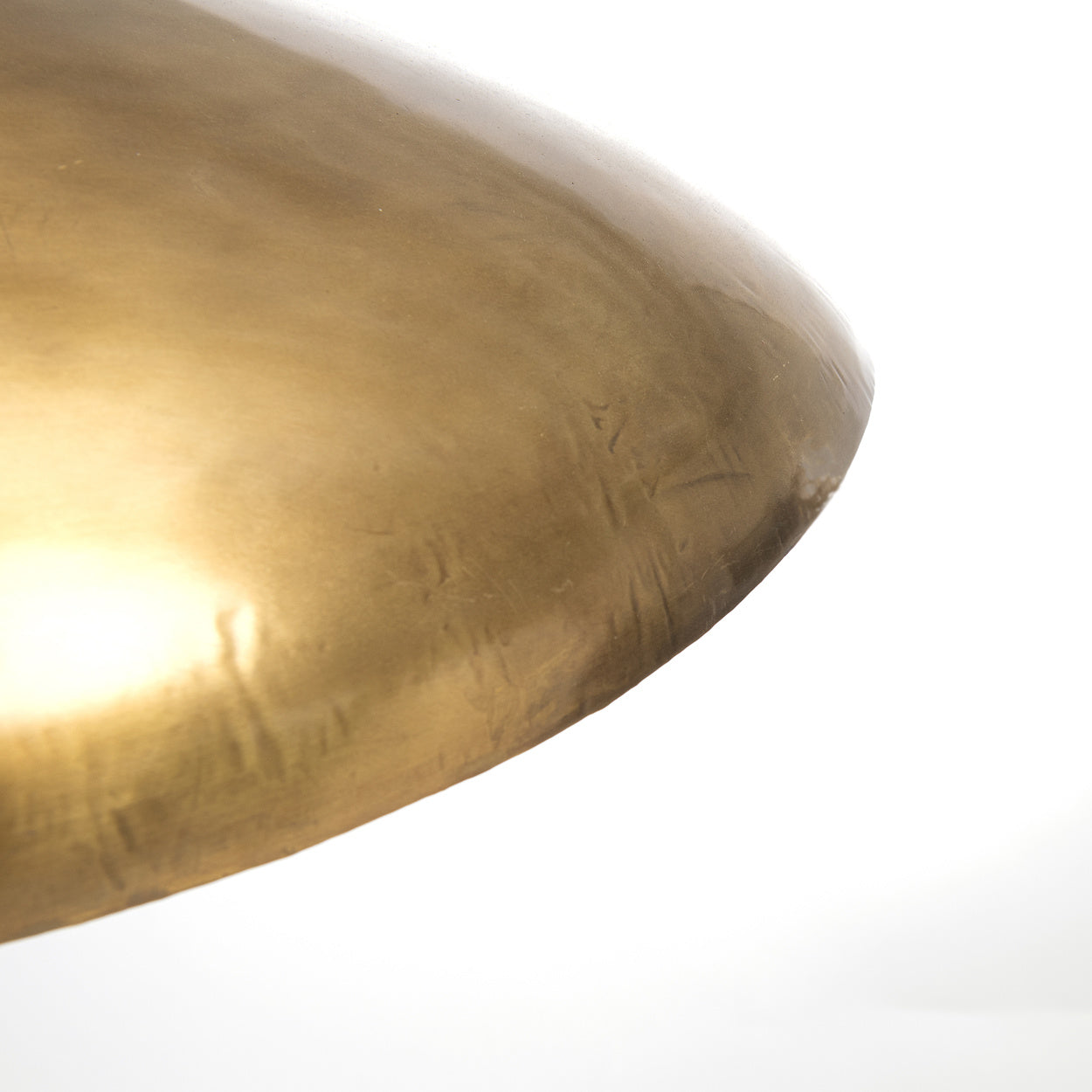 Gouden metalen lampenkap met glad, glanzend oppervlak op witte achtergrond, strakke verfijnde uitstraling.