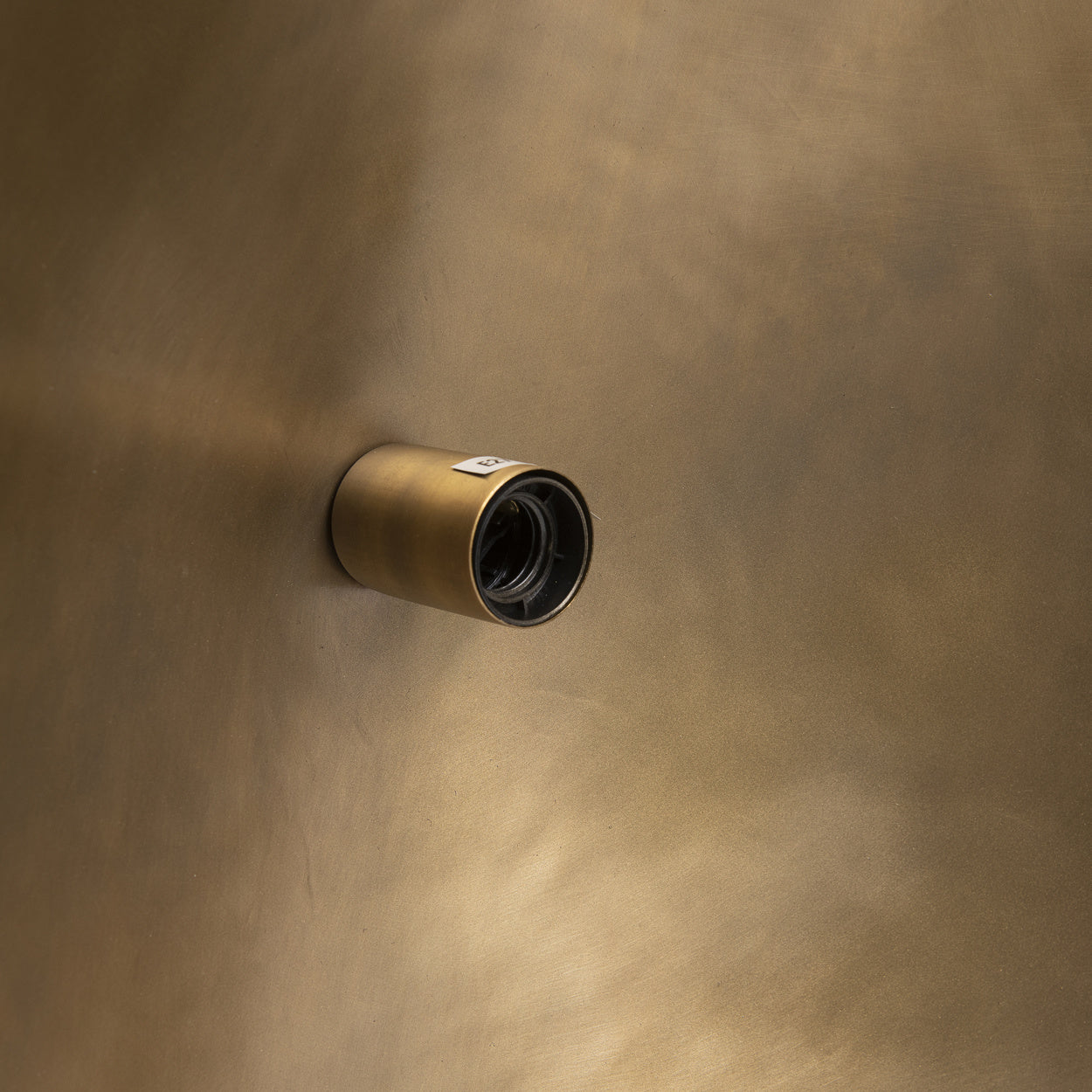 Ronde gouden wandspot steekt uit tegen een matte metalen achtergrond, waardoor een luxe uitstraling ontstaat.