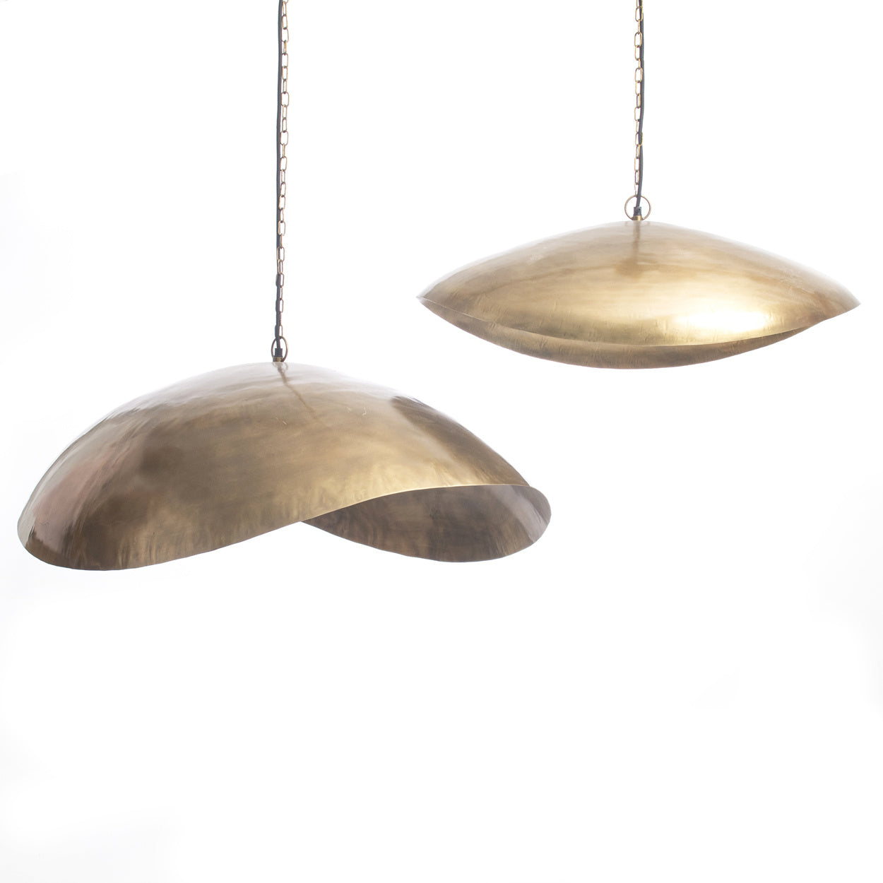 Twee hangende lampenkappen van gepolijst goudkleurig metaal, met een elegant asymmetrisch ontwerp.