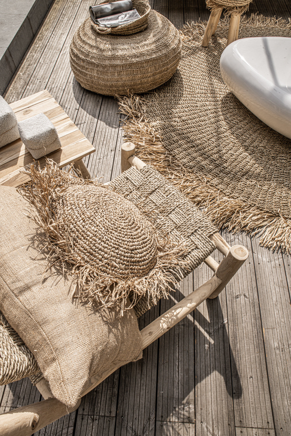 Rustieke houten terras met geweven rotan meubels en decor, omgeven door een zonnige, natuurlijke sfeer.