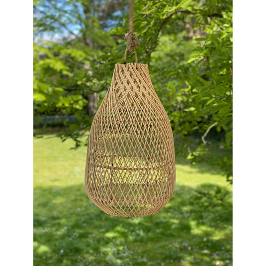 Gevlochten houten lamp in de vorm van een druppel, hangend in een groene tuin vol zonlicht.