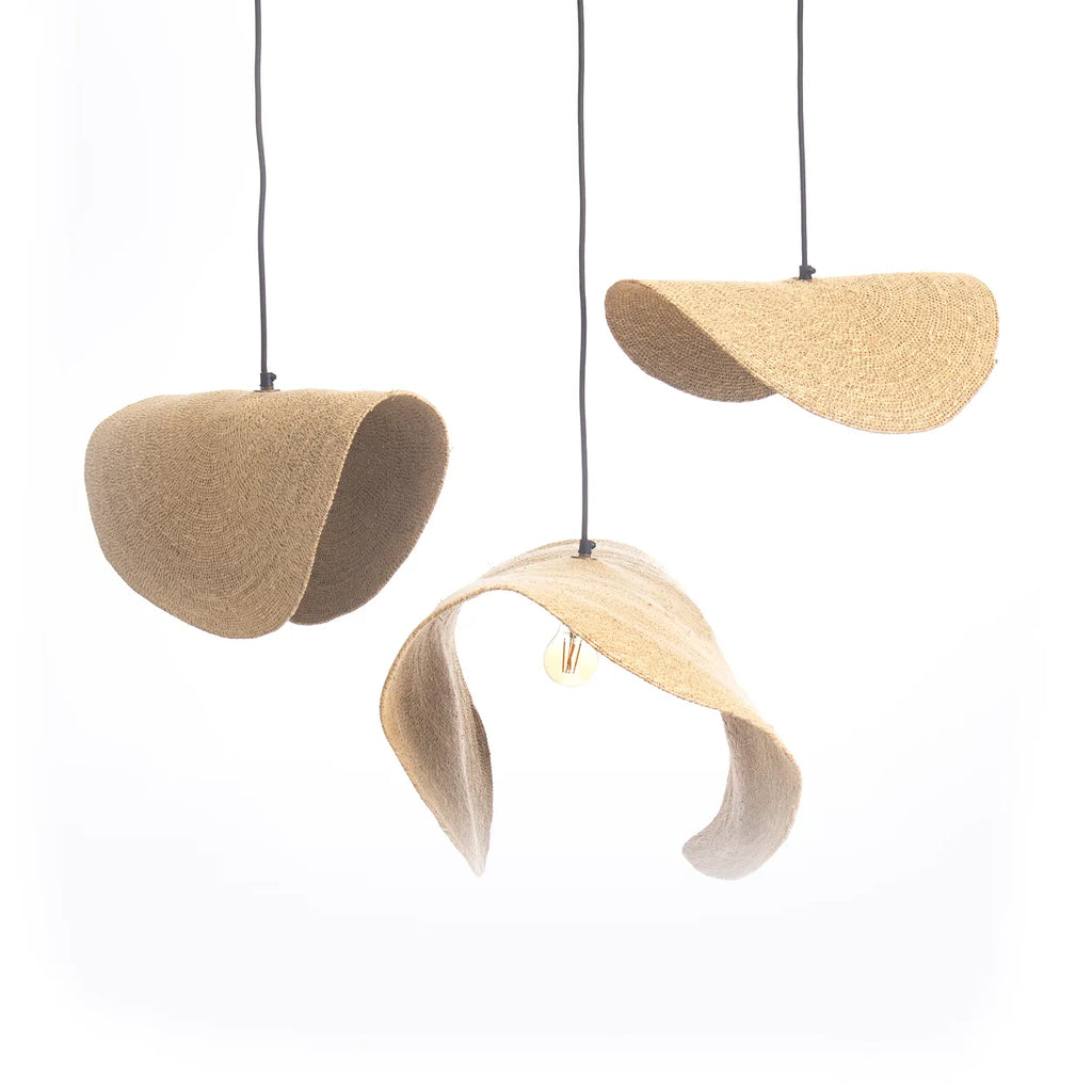 Drie hanglampen van geweven beige stof, elegant en modern vormgegeven, hangen aan dunne zwarte snoeren.
