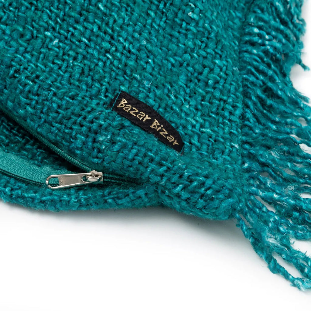 Turquoise geweven tas met ritssluiting, franjes en zwart label met gouden tekst "Bazar Bizar".