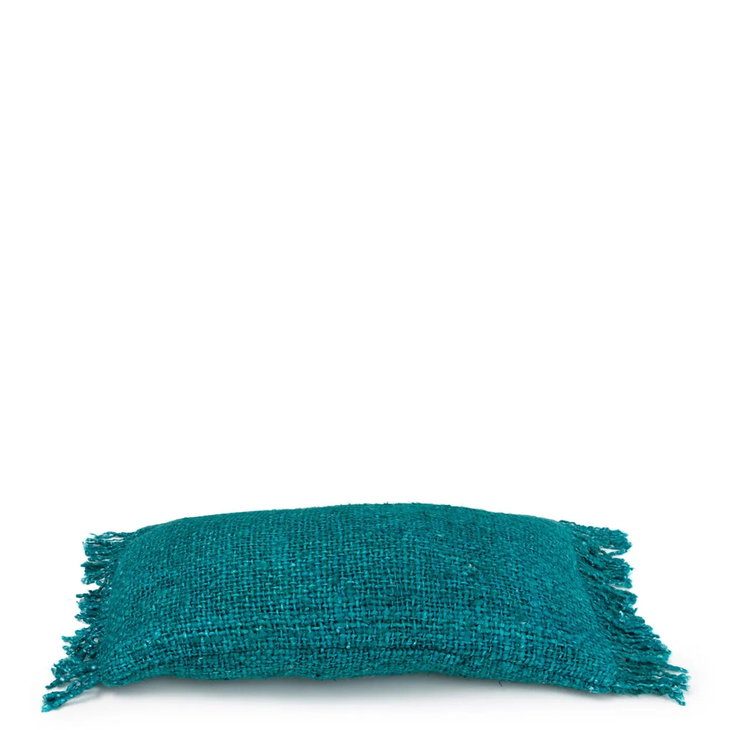 Sierkussen met franjes in turquoise geweven stof tegen een witte achtergrond, comfortabele uitstraling.