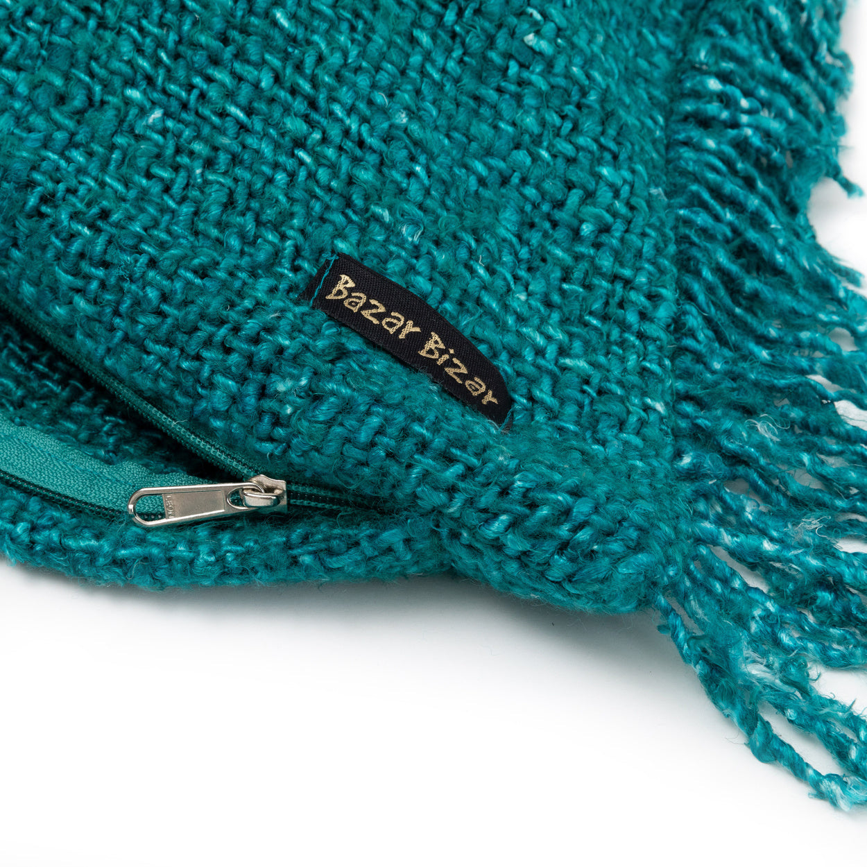 Turquoise brei-dekbedovertrek met franjes en ritssluiting, label "Bazar Bizar" zichtbaar.