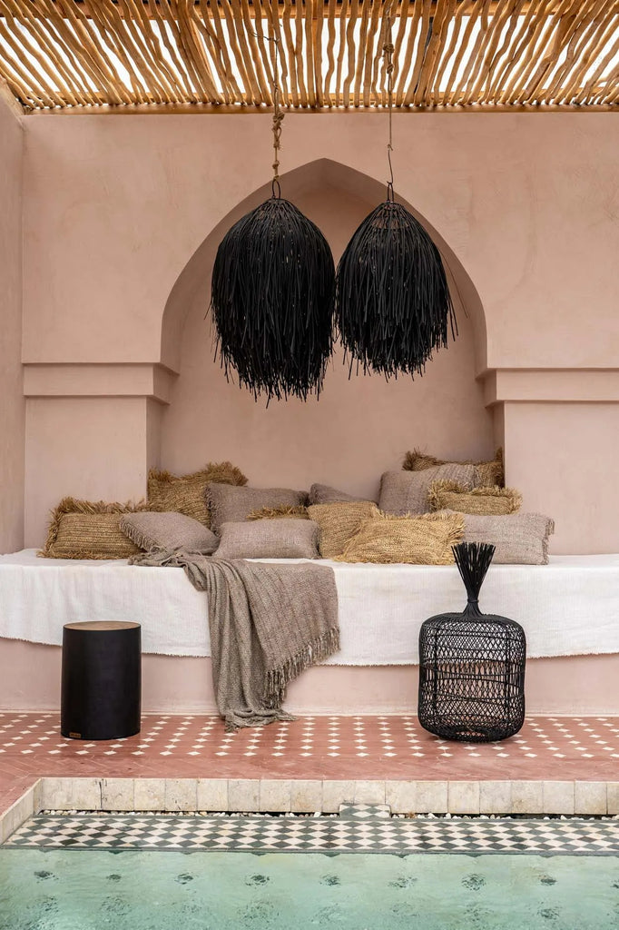 Elegant loungehoek met bruine kussens en lampen boven mozaïektegels, naast een rustig zwembad.